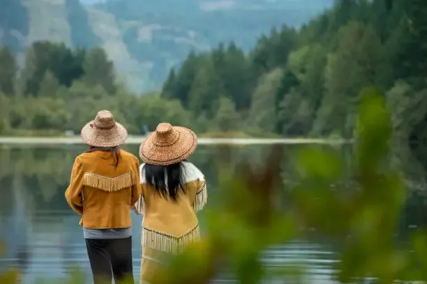 Two people looking out over a lake surrounded by forest